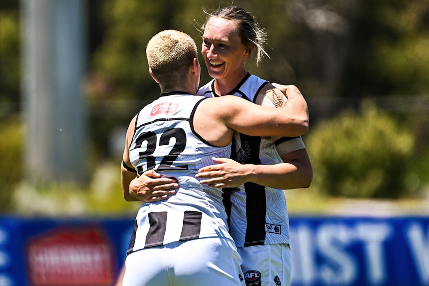 Two Collingwood AFLW players celebrate a goal against West Coast.