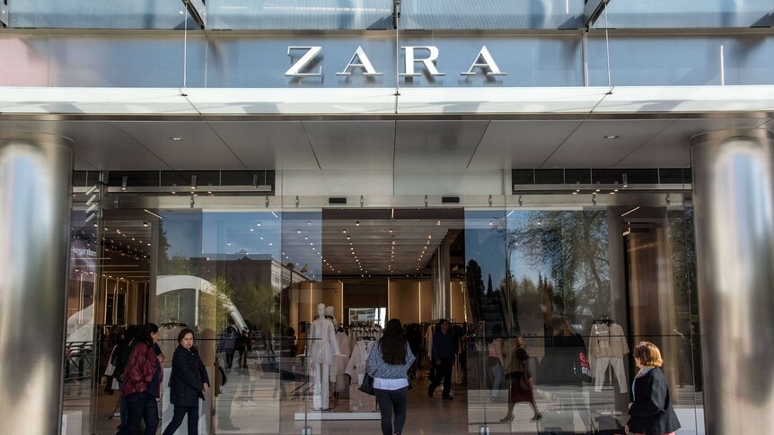 Shoppers mill around the automatic glass doors of the Zara store's imposing chrome and glass exterior.