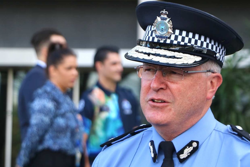 Police Commissioner Chris Dawson in full uniform speaks into microphones at the front of the police headquarters building.