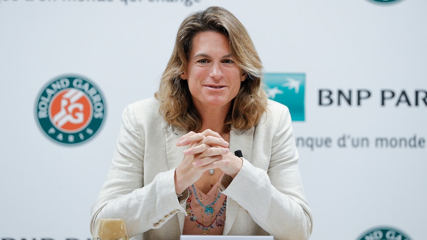French Open tournament director Amelie Mauresmo sits at a desk and looks out at the media in a press conference.