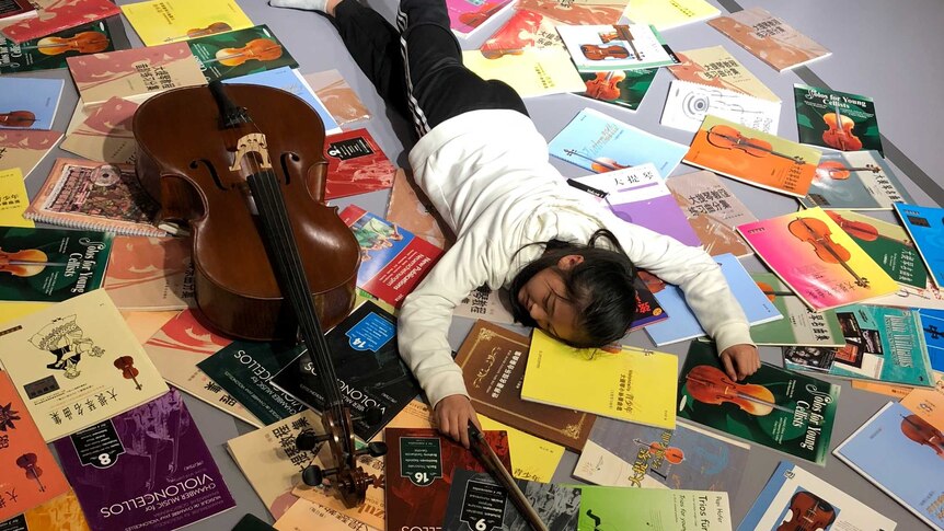 A young cello student posed for the falling stars challenge with her instrument and books on the floor.