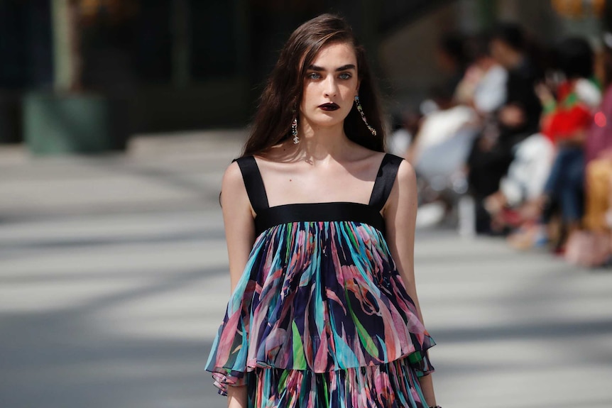 A model walks the catwalk wearing a sleeveless multi-coloured top