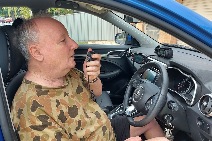 A man operates a radio in a car