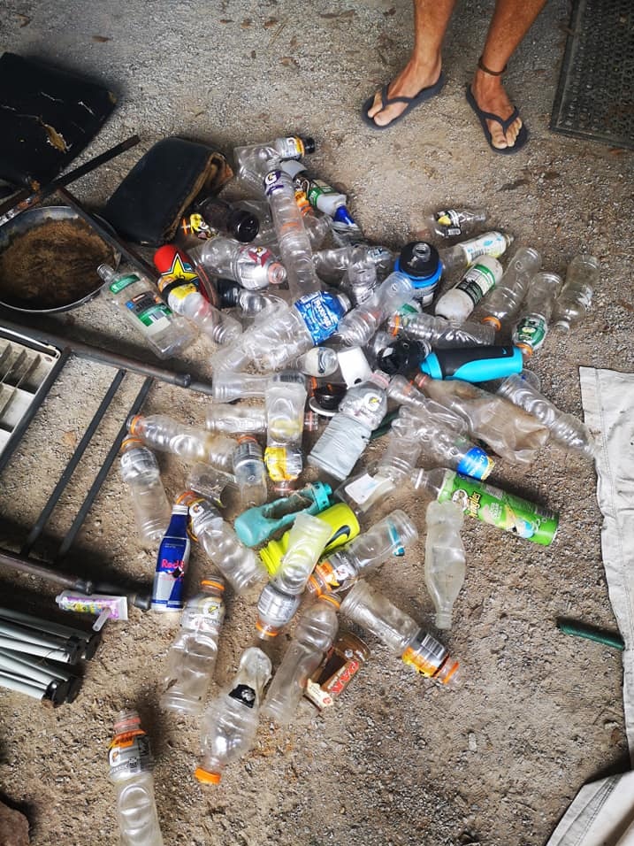 Dozens of empty sports drink bottles on a concrete floor.