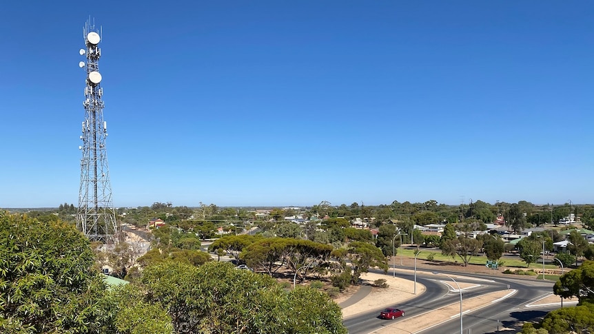 A large tower rises above the trees and roadways of a small town.