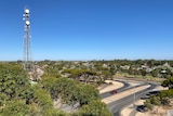 A large tower rises above the trees and roadways of a small town.