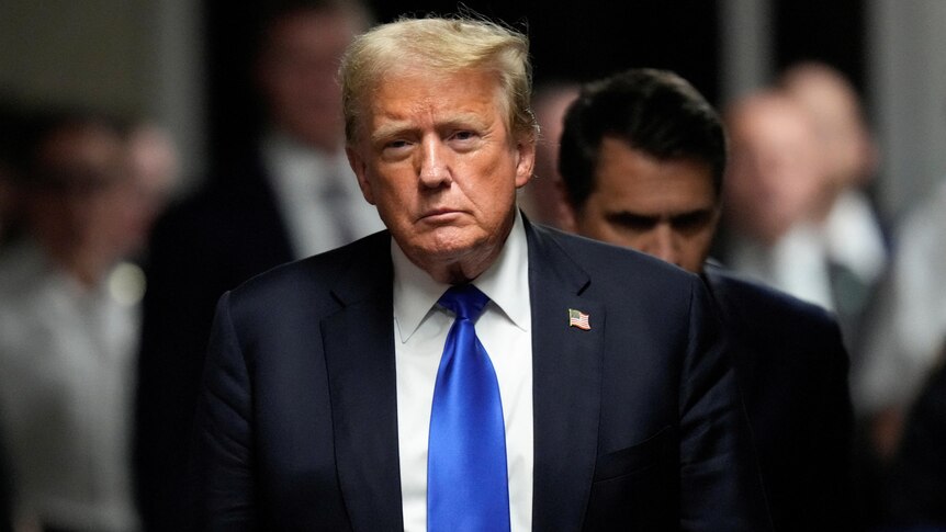 Donald Trump, with a stern look on his face, outside a court building.