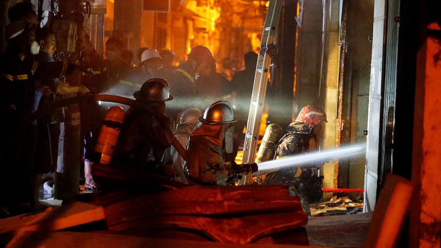 Firefighters point hose at fire