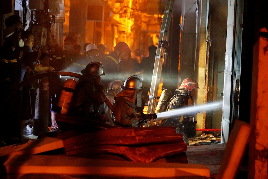 Firefighters point hose at fire