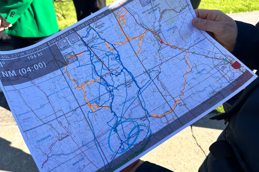 A map being held in someone's hands with orange lines around.