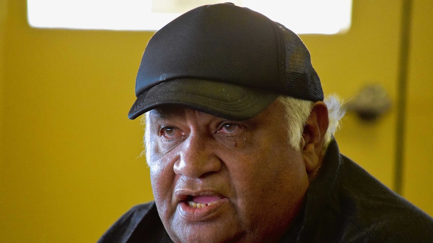 An Aboriginal man wearing a black cap and shirt