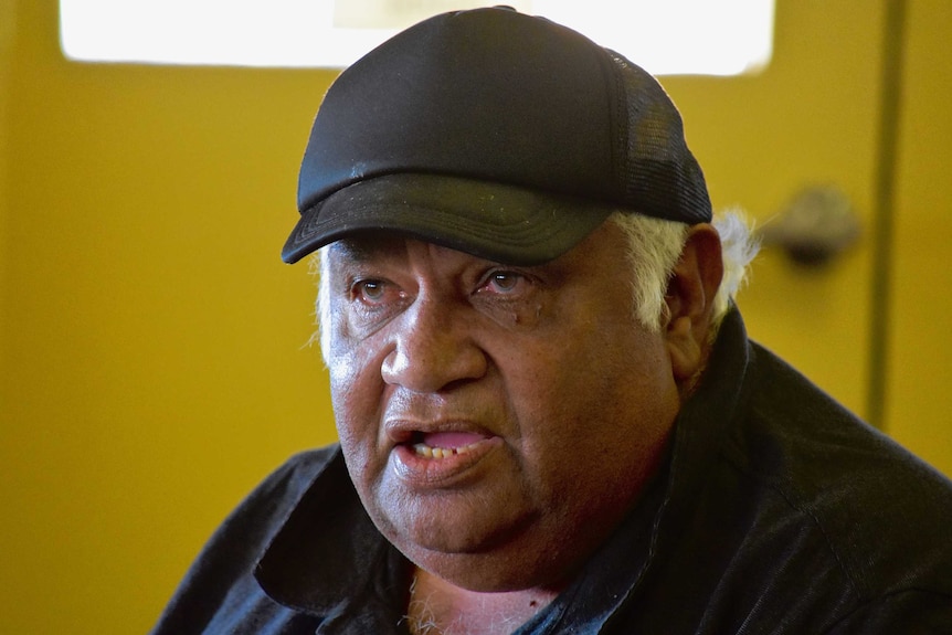 An Aboriginal man wearing a black cap and shirt