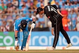 Indian cricketer Virat Kohli bends down to stretch his foot as a New Zealand player leans in to check on his welfare.