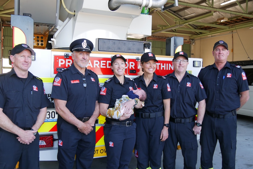 Sam holding baby Andy next to Liz and the rest of the fire crew.