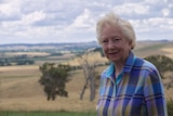 Trish Worth standing in front of paddocks and trees of a country property