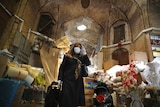 A woman wearing a protective face mask and gloves in a building in Iran.