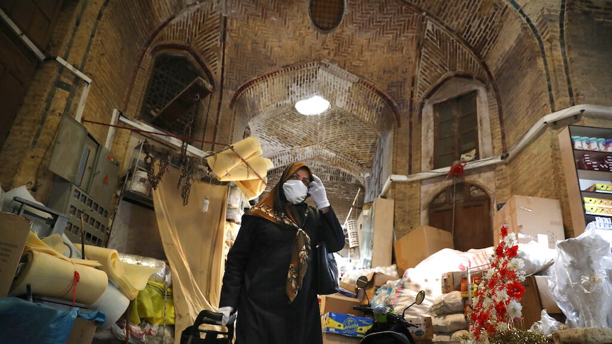 A woman wearing a protective face mask and gloves in a building in Iran.