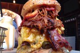 A hamburger overloaded with cheese, bacon, several patties