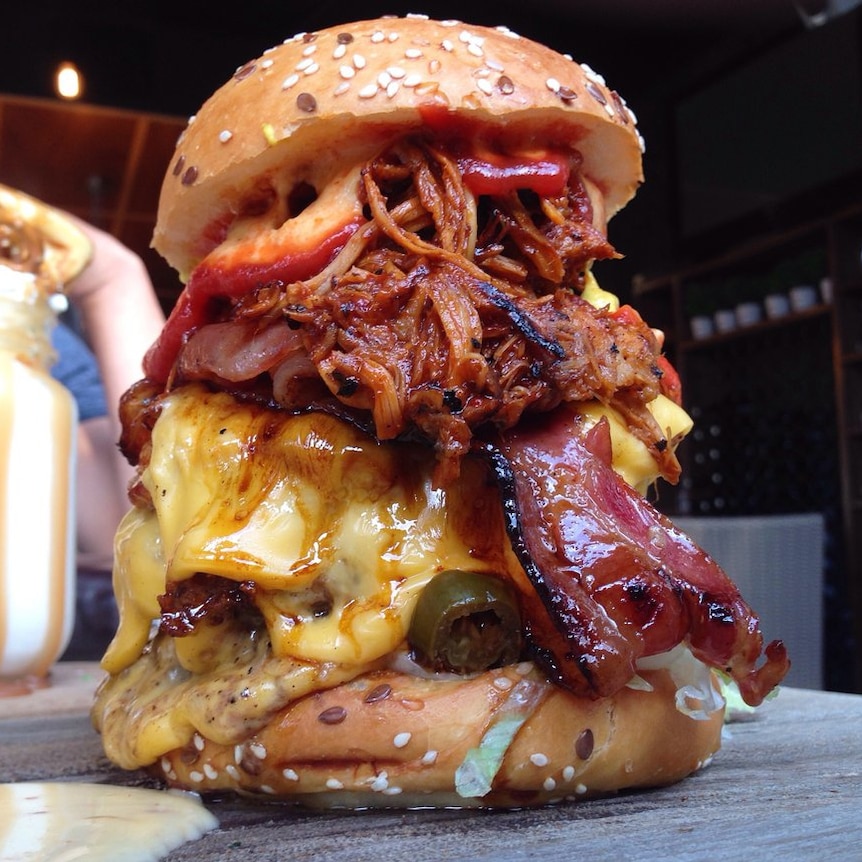 A hamburger overloaded with cheese, bacon, several patties