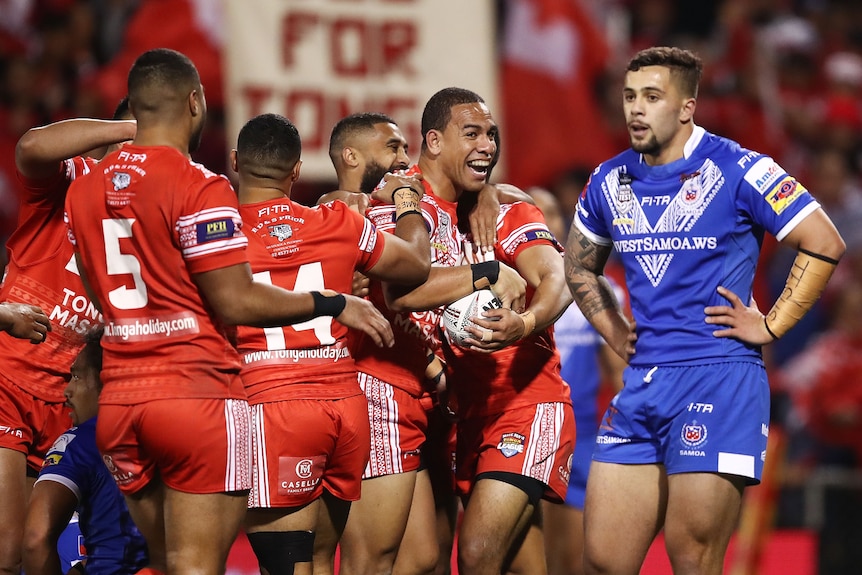 A man celebrates scoring a try in an NRL match