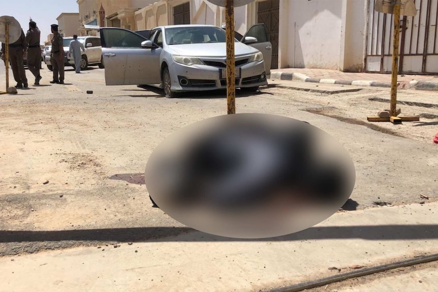 A blurred photo of what may be a dead body on the ground in front of a building in Saudi Arabia
