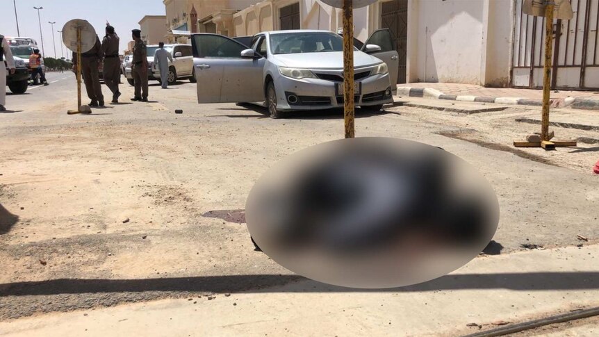 A blurred photo of what may be a dead body on the ground in front of a building in Saudi Arabia