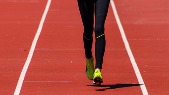 Woman running on a red track field.