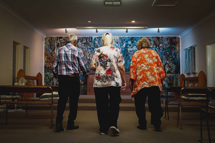 Three people walk down the hallway of a church