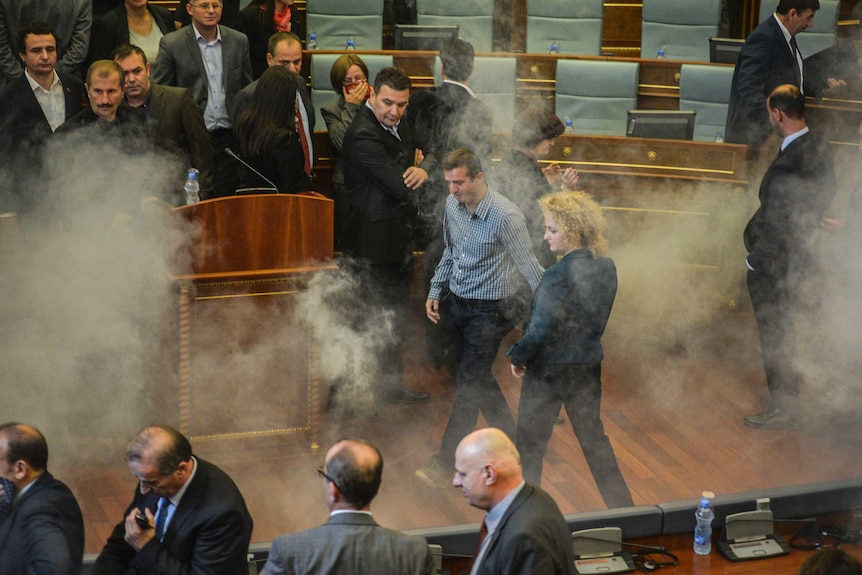 Parliamentarians disperse as a white cloud of tear gas rises in Kosovo's parliament