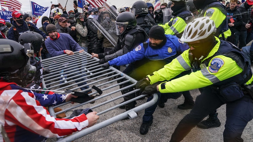 Trump supporters pull a police barrier from all sides as they try to break through a police line.