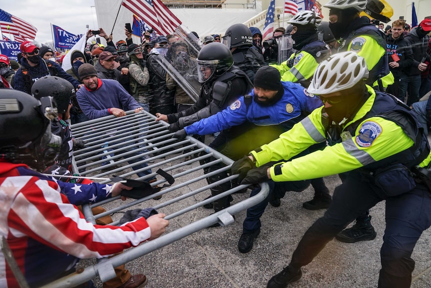 Trump supporters pull a police barrier from all sides as they try to break through a police line.