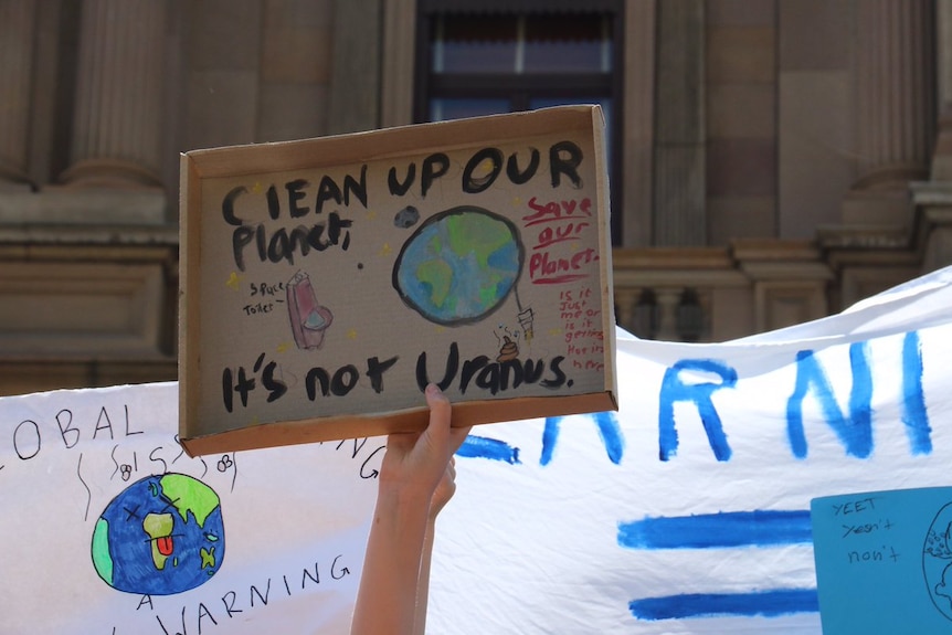 A hand holding up a sign saying: "Clean up our planet, it's not Uranus."