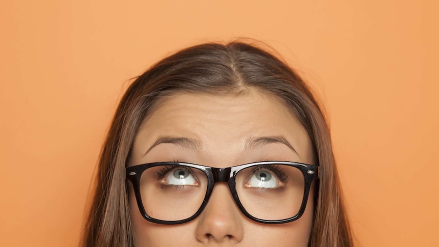 A woman wearing glasses looks up.
