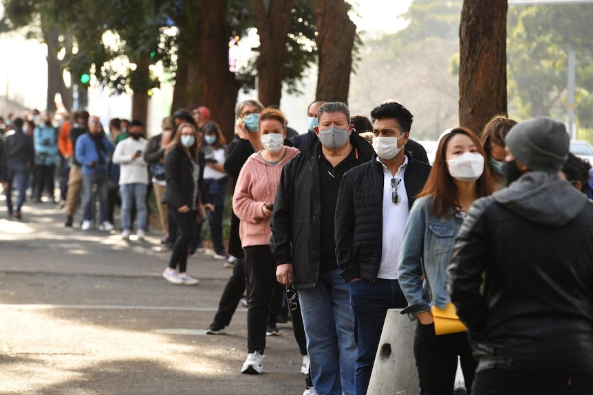 People are seen queued to receive their vaccination all are wearing face masks.