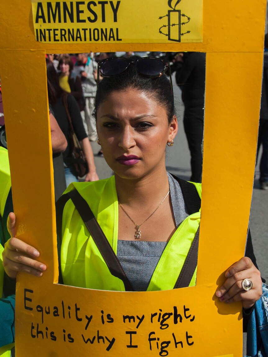 A Tunisian woman holds a placard saying 'Equality is my right, this is why I fight'