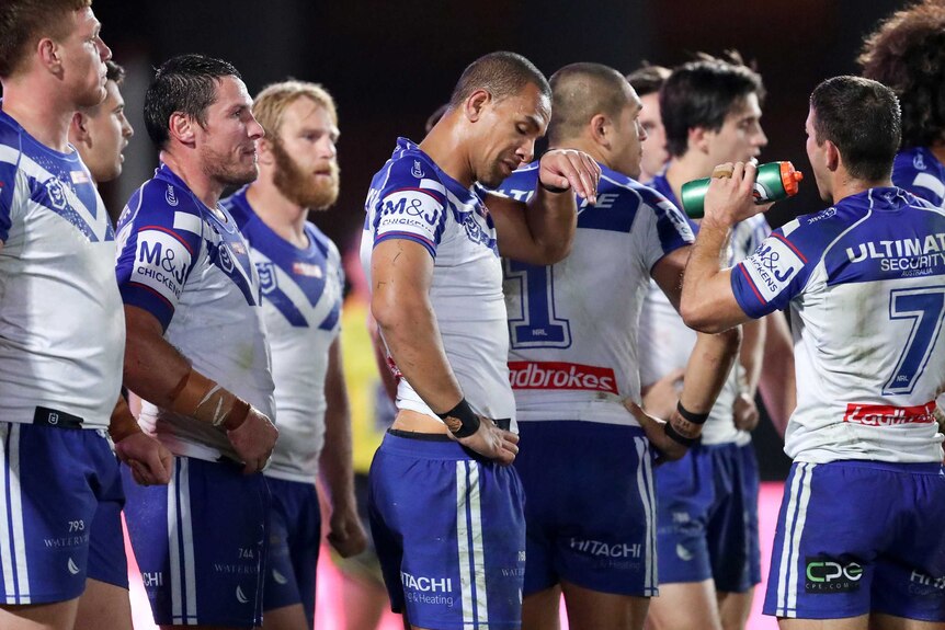 Bulldogs players look disheartened as they stand together during a game.