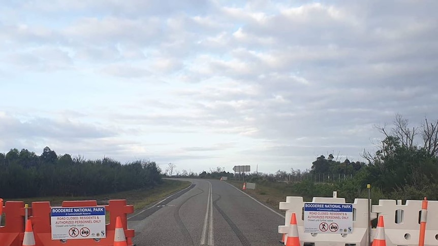 A roadblock stands across a road leading into a national park.