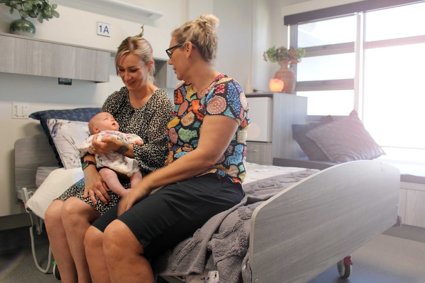 two women sitting on hospital bed with baby