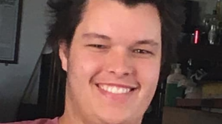 A man with pointy hair and maroon t-shirt smiling at the camera