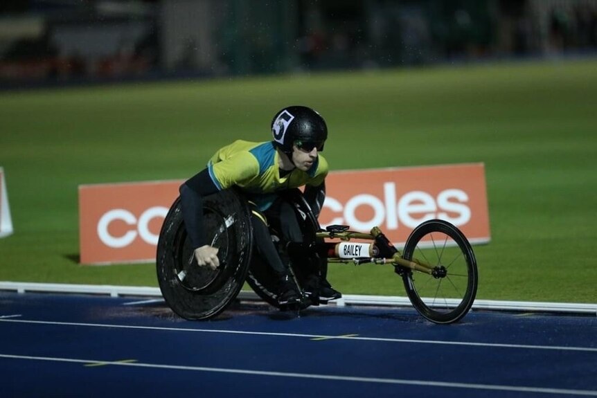 A Paralympian racing down a track in a three-wheeled chair.