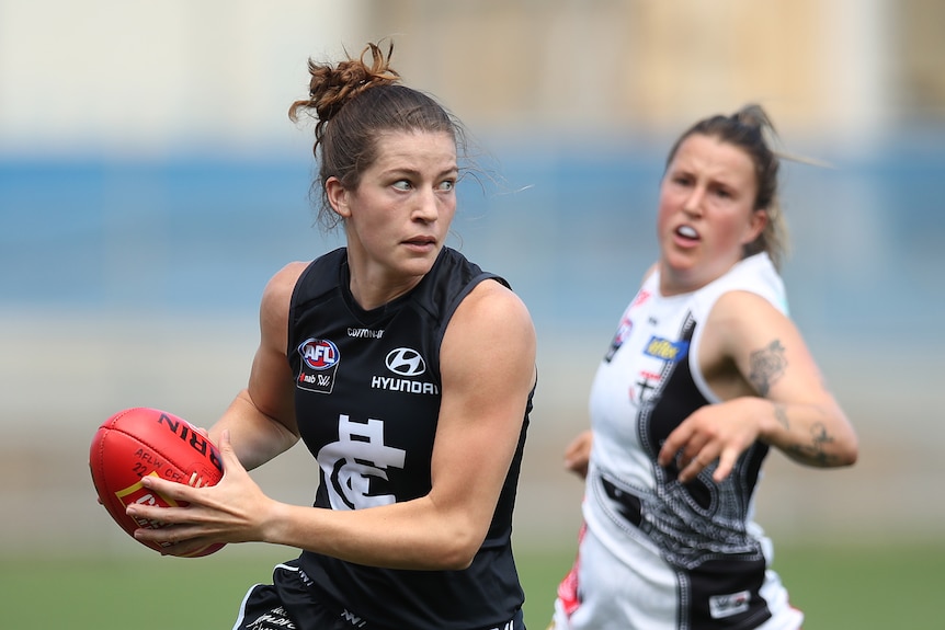 An AFLW player looks infield as she runs with the ball, while a tired defender is left in her wake.