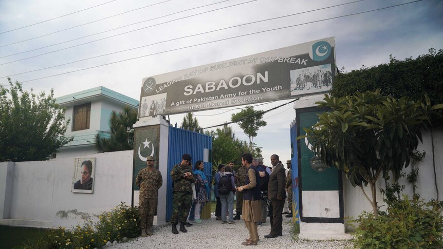 A group of people mill around the entrance of a rehab centre in Pakistan