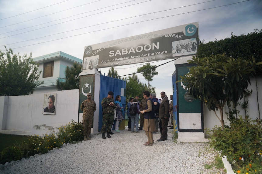 A group of people mill around the entrance of a rehab centre in Pakistan