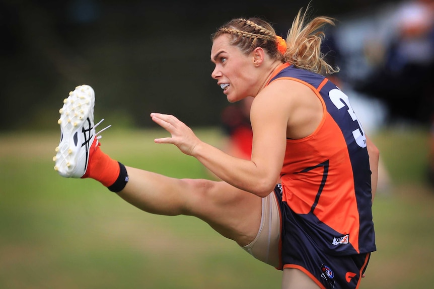 Jacinda Barclay grimaces while following through after a mighty drop punt