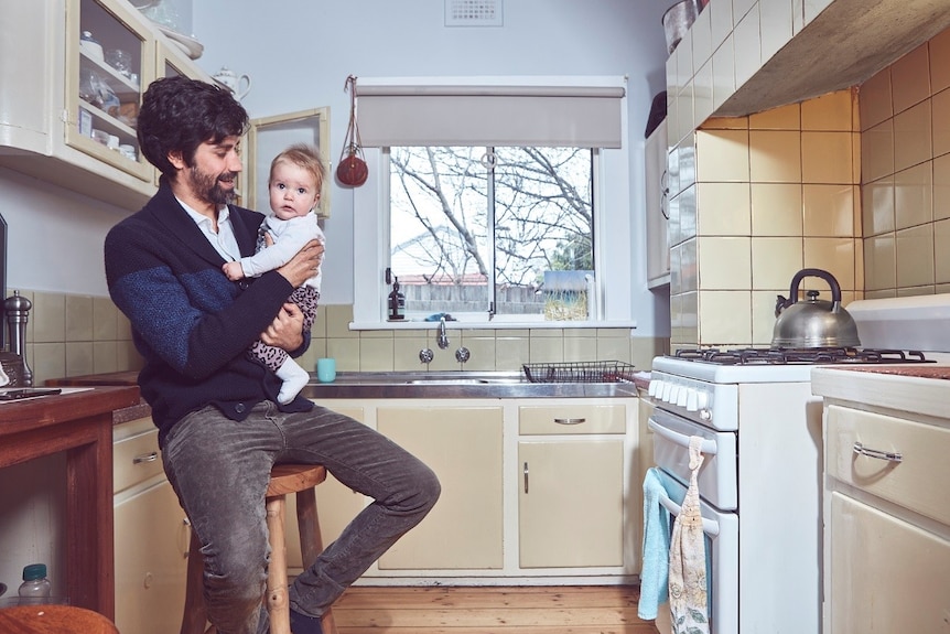 Brett Lee with his baby in the kitchen at home