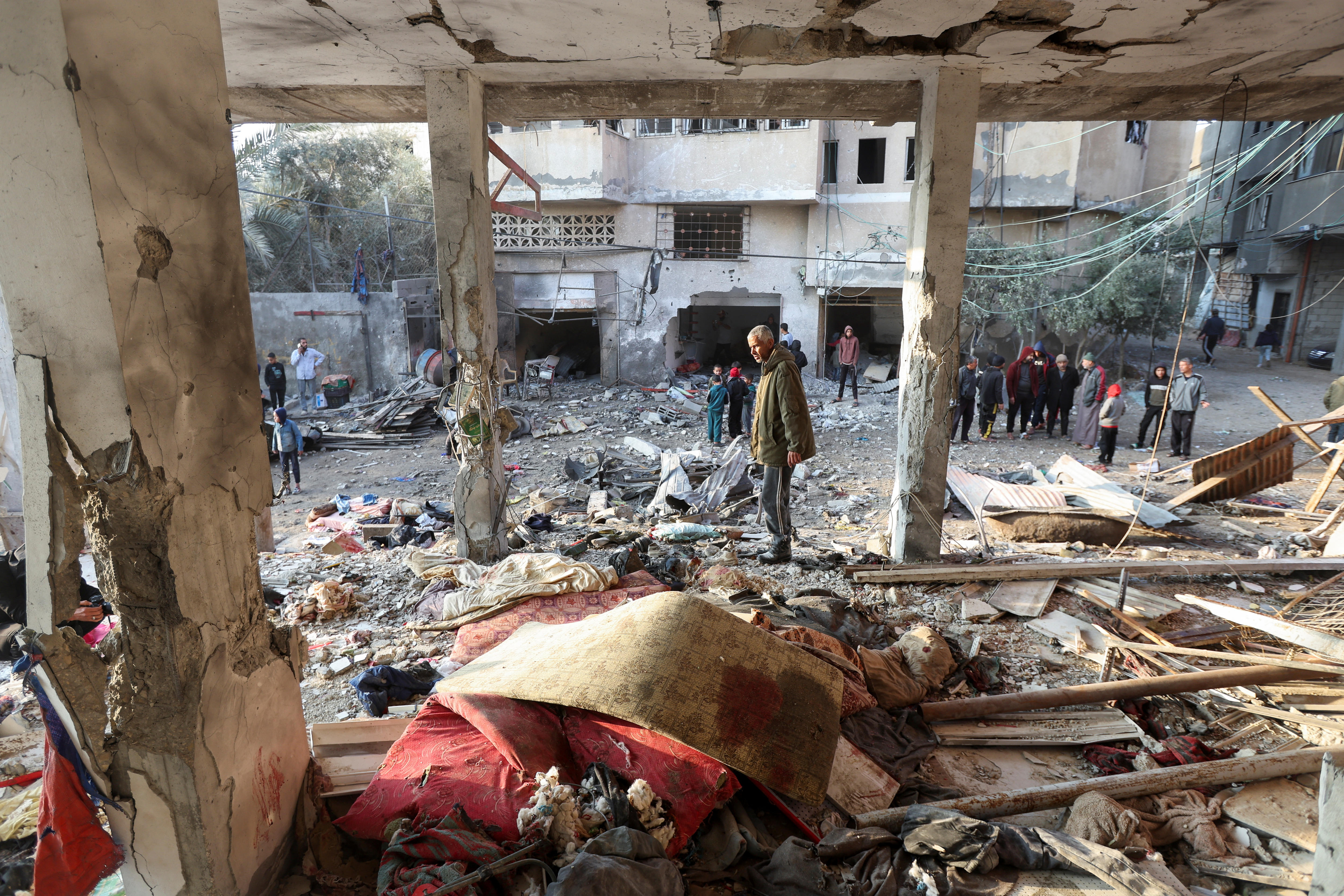 People looking through the rubble on the ground floor of a bombed building following an air strike.