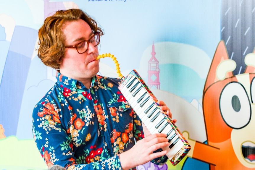 A man in a colourful shirt plays the melodica
