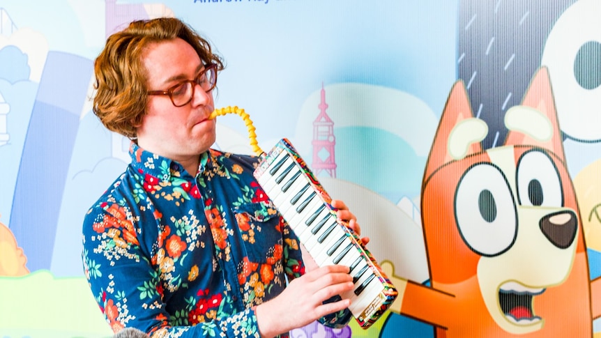 A man in a colourful shirt plays the melodica