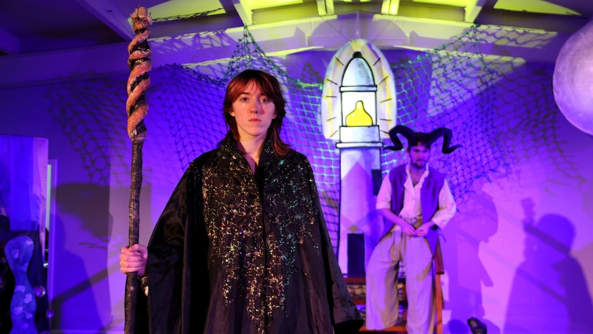 A year 11 school student dressed as a wizard on stage with lighthouse in background.