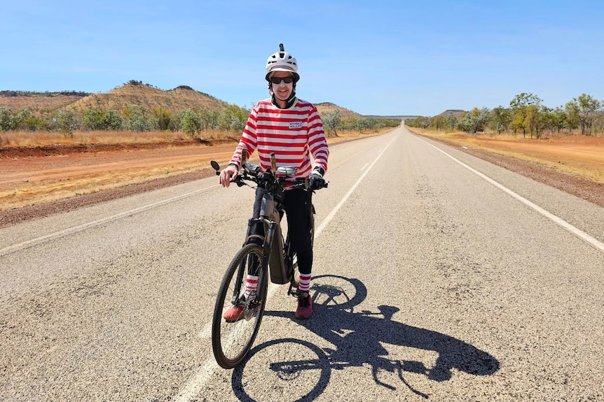 A man in a red-and-white shirt on a bike.